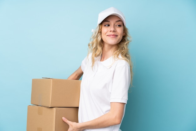 Young delivery woman on blue laughing