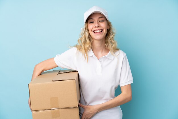 Young delivery woman on blue laughing