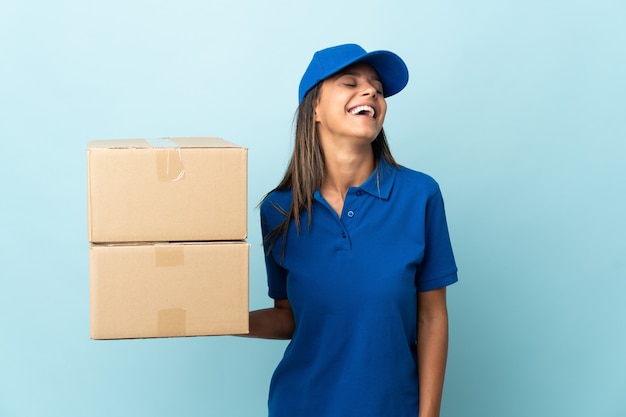Young delivery woman isolated on blue background laughing