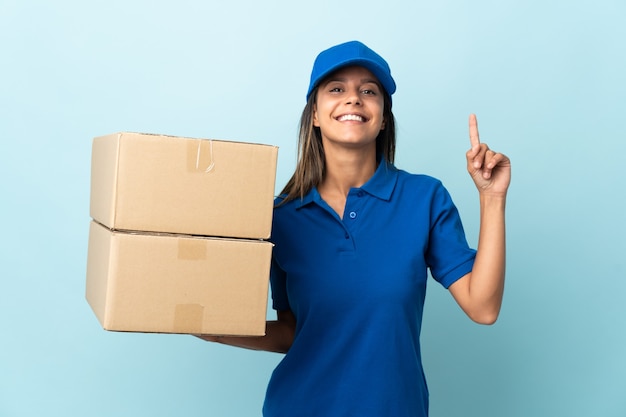 Young delivery woman isolated on blue background pointing up a great idea