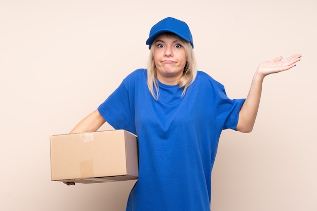 Young delivery woman over isolated wall having doubts with confuse face expression