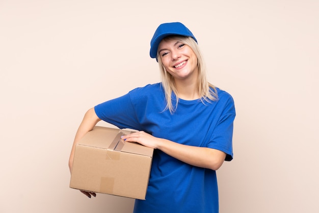 Young delivery woman over isolated wall laughing