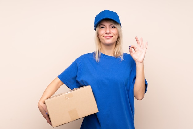 Young delivery woman over isolated wall showing an ok sign with fingers