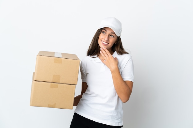 Young delivery woman over isolated white background looking up while smiling