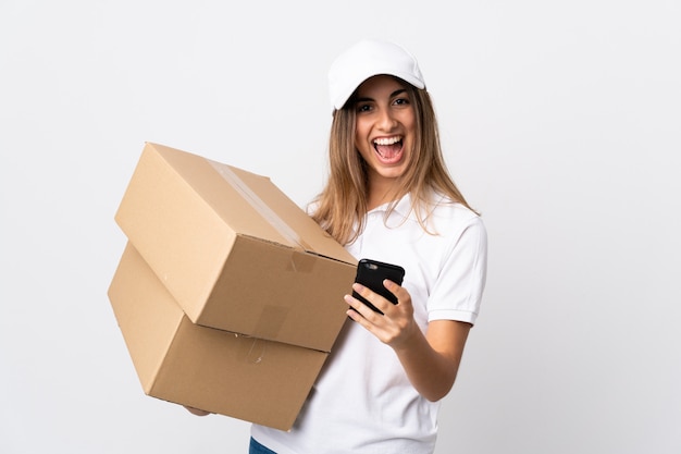 Young delivery woman over isolated white background surprised and sending a message