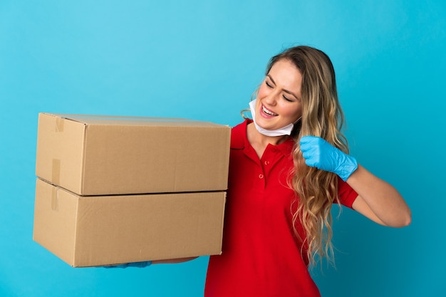 Young delivery woman isolated on white celebrating a victory