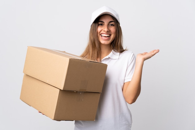 Young delivery woman on isolated white holding copyspace imaginary on the palm to insert an ad