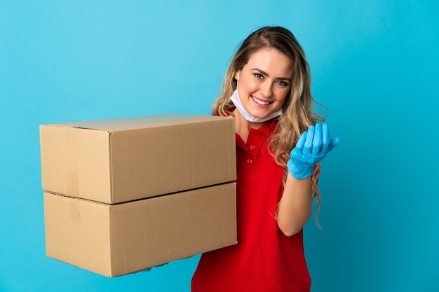 Photo young delivery woman isolated on white inviting to come with hand. happy that you came