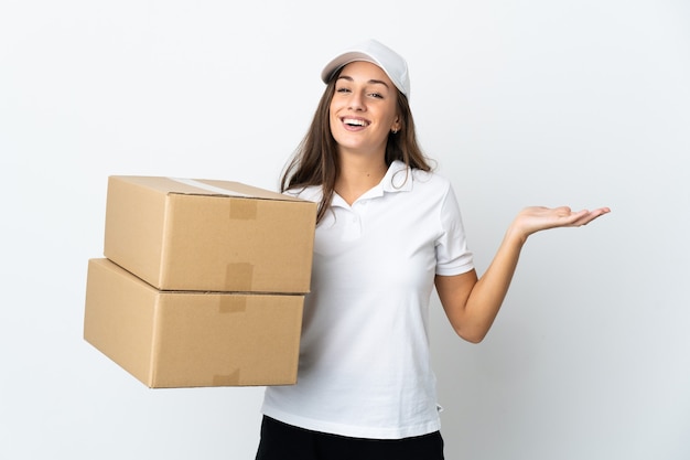 Young delivery woman over isolated white wall holding copyspace imaginary on the palm to insert an ad