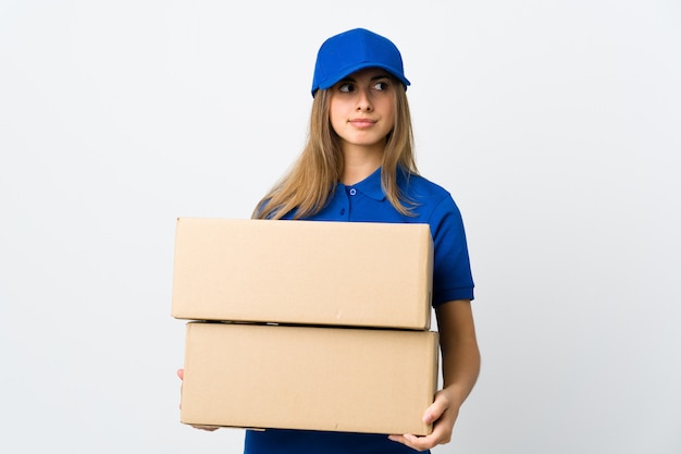 Young delivery woman over isolated white wall making doubts gesture looking side