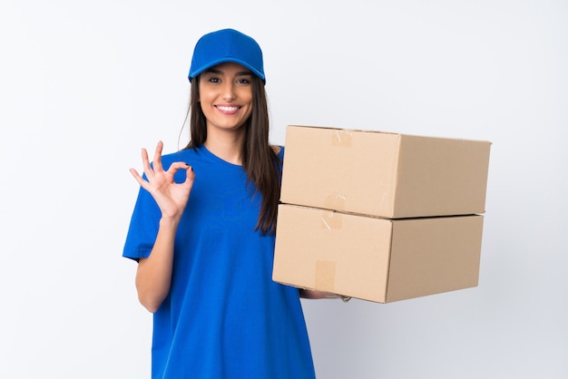 Young delivery woman over isolated white wall showing an ok sign with fingers