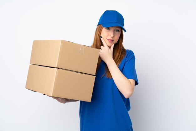 Young delivery woman over isolated white wall thinking an idea