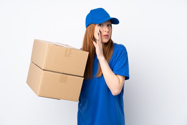 Young delivery woman over isolated white wall whispering something