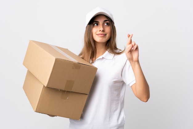 Young delivery woman on isolated white with fingers crossing and wishing the best