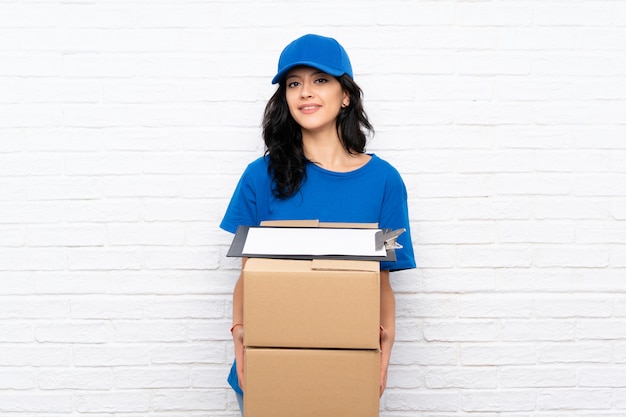 Photo young delivery woman over white brick wall