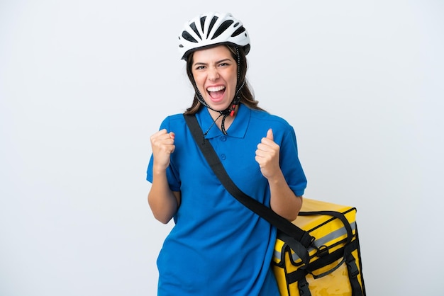 Young delivery woman with thermal backpack isolated on white background celebrating a victory in winner position