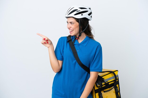 Young delivery woman with thermal backpack isolated on white background pointing finger to the side and presenting a product