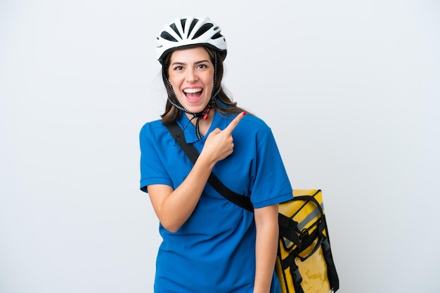 Young delivery woman with thermal backpack isolated on white background surprised and pointing side