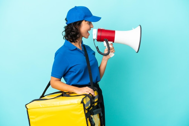 Young delivery woman with thermal backpack shouting through a megaphone