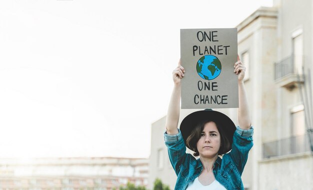 Young demonstrator activist holding banner during climate\
change protest outdoor ecology