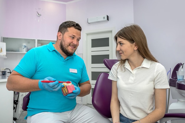 Young dentist conducts a consultation for a girl with a sore tooth at his appointment