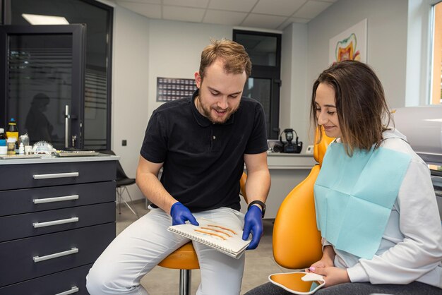 Il giovane dentista consulta una paziente in uno studio dentistico