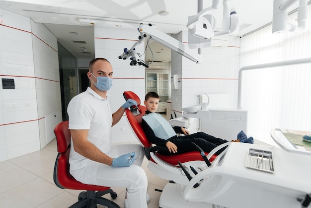 A young dentist examines and treats the teeth of an eightyearold boy in modern white dentistry closeup Dental prosthetics treatment and teeth whitening Modern dentistry Prevention