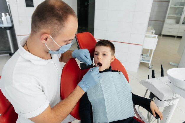 A young dentist examines and treats the teeth of an eightyearold boy in modern white dentistry closeup Dental prosthetics treatment and teeth whitening Modern dentistry Prevention