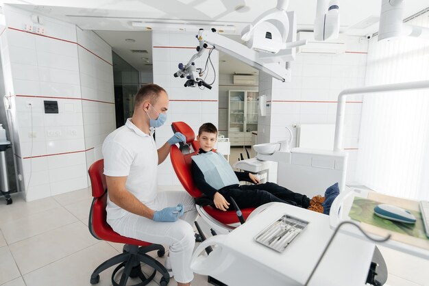 A young dentist examines and treats the teeth of an eightyearold boy in modern white dentistry closeup Dental prosthetics treatment and teeth whitening Modern dentistry Prevention