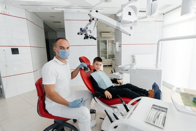 A young dentist examines and treats the teeth of an\
eightyearold boy in modern white dentistry closeup dental\
prosthetics treatment and teeth whitening modern dentistry\
prevention