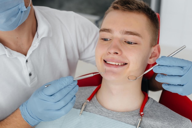 A young dentist examines and treats the teeth of a young man in modern white dentistry closeup Dental prosthetics treatment and teeth whitening Modern dentistry Prevention