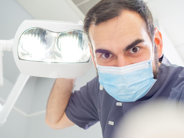 Young dentist wearing a mask and gloves in a clinic during a clinical checkup