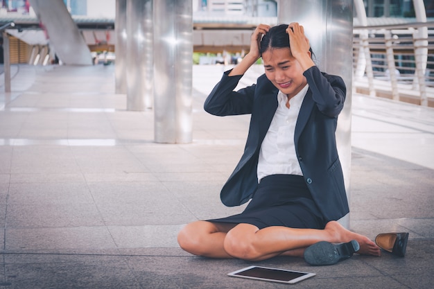 Young depressed businesswoman sitting on the floor