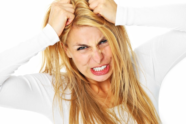 a young depressed woman tearing out her hair over white background