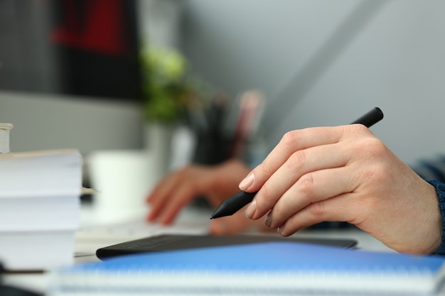 A young designer holds a pen from a tablet in his