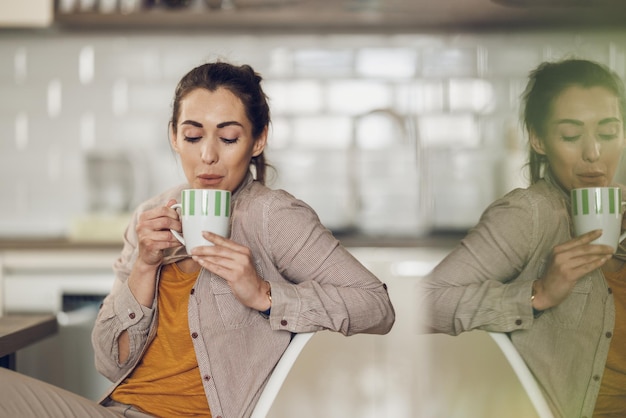 집에서 일하는 동안 앉아서 커피 한 잔을 즐기는 젊은 디자이너 여성.