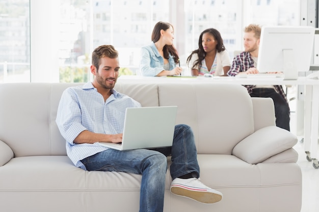 Young designer working on his laptop on the couch