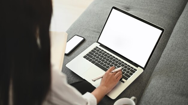 Young designer working with laptop on couch at home