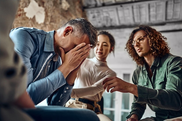 Photo young despair man crying during group therapy