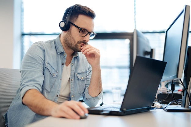 A young developer is working at his desk with his headphones on.