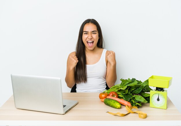 Young dietician asian woman isolated on white background cheering carefree and excited. Victory concept.