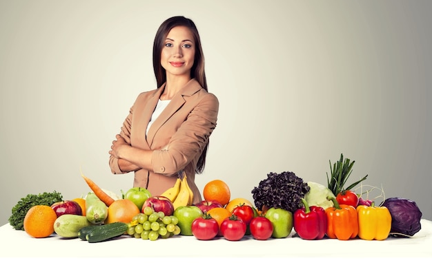 Young dietology professional with fruits on table and light background