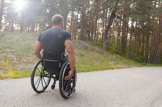 Young disabled athlete in a walking pine park in a wheelchair