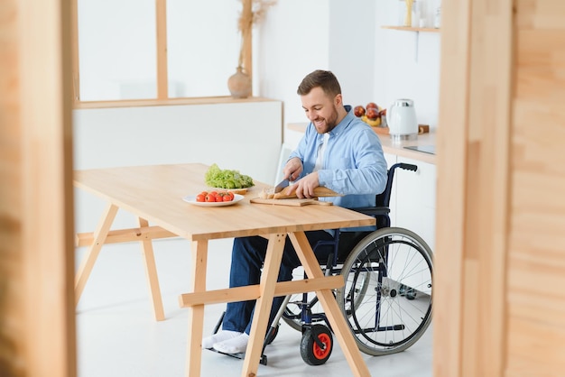 Young Disabled Man Sitting On Wheel Chair Preparing Food In Kitchen