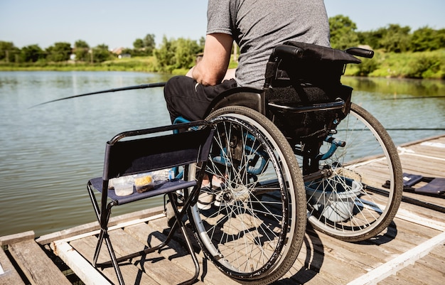 Giovane uomo disabile in una pesca in sedia a rotelle.