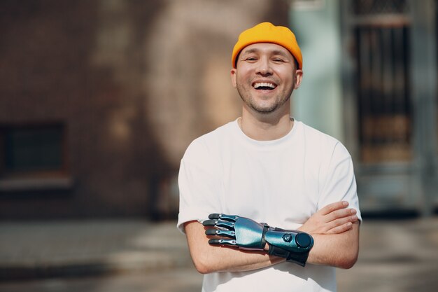 Young disabled man with artificial prosthetic hand in casual clothes laughing portrait