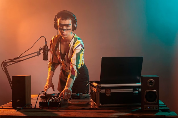 Young disc jockey mixing music on turntables, playing techno sounds with audio equipment in studio. Woman working as dj to use mixer and stereo instrument, electronics performance.