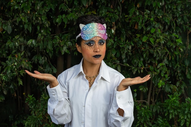 Giovane donna travestita con trucco e maschera colorata sopra la testa su sfondo naturale