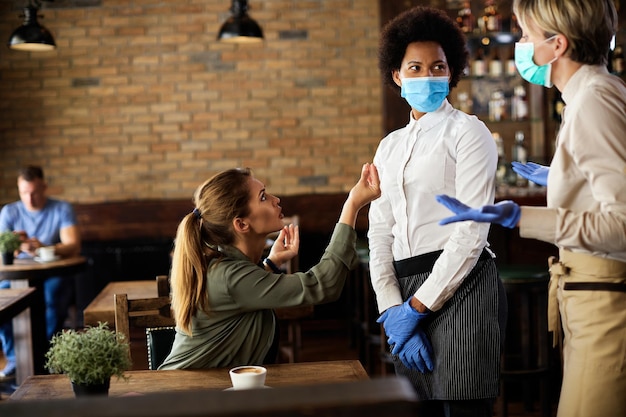 Young displeased woman arguing with waitresses in a cafe