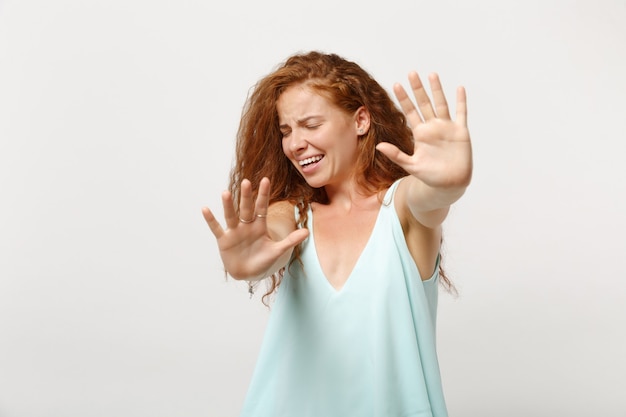 Young dissatisfied redhead woman in casual clothes posing isolated on white background. People lifestyle concept. Mock up copy space. Standing with outstretched hands, showing stop gesture with palms.